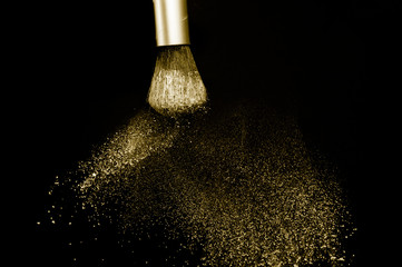 gold powder splash and silver brush for makeup artist or beauty blogger in black background, look like a luxury mood.