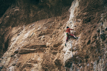 man climbs an overhanging rock, hard route 7c, lead.