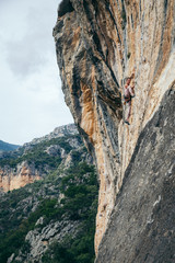 woman climbs a rock in Greece and beautiful forest and cliff landscape on the background