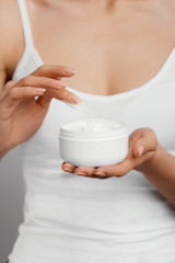 Closeup shot of woman hands holding cream and applying moisturizing hand cream. Beautiful female hands with cream. Hand Skin Care. A woman uses body lotion on your arms. Beauty And Body Care Concept