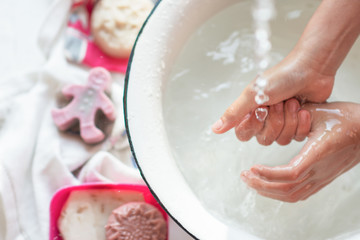 Child’s hands under white bowl with water upon water stream, colorful soaps on Child’s hands under white bowl with water upon water stream, colorful sa white material, cleanliness and hygiene concept 