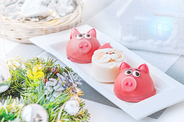 Marzipan in the shape of the symbol of the new year pink - pig, sweet delicate macaroons, marshmallows, peanuts in sugar pastel colors on a light background