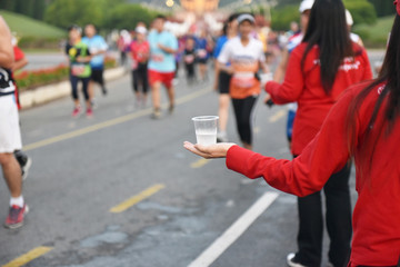 Close up of volunteers hands offering water during a Marathon. Use of selective focus. Lots of...