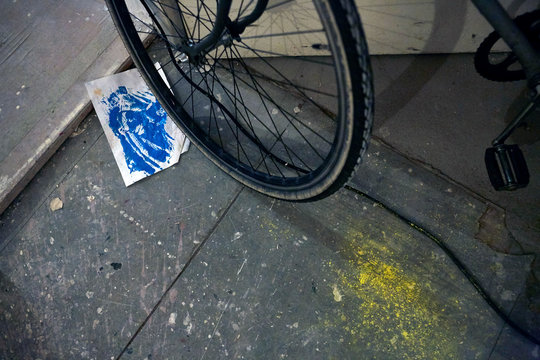 Fahrrad in K&uuml;nstler Atelier mit blauen und gelben Farbflecken auf Boden
