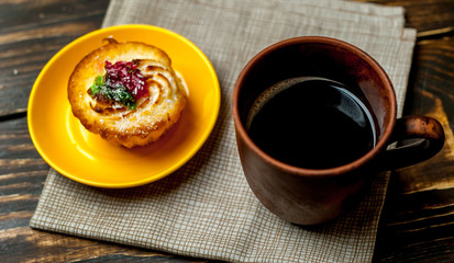 cup of coffee, cake in a plate on a wooden background