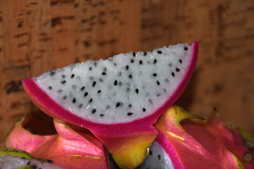 macro shot of slice of dragon fruit in front of cork background , pitaya blanca or white-fleshed...