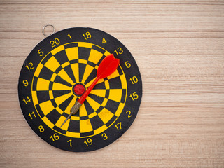 Dart arrow and dartboard on brown wooden background