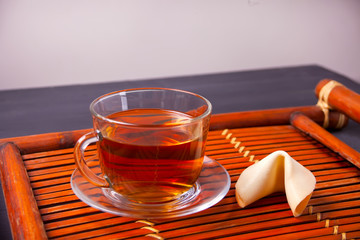 Cup of tea with fortune cookie in oriental style on a wooden background