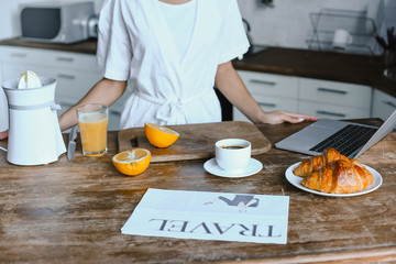 cropped image of mixed race girl in white robe standing at table in morning in kitchen