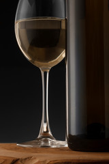 White wine bottle and glass on the black background