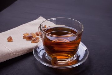 Cup of hot tea with caramel sugar on a wooden table