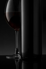 Red wine bottle and glass on the black background