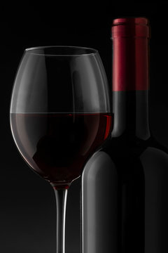 Red wine bottle and glass on the black background