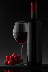 Red wine bottle and glass on the black background