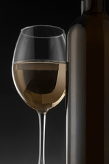 White wine bottle and glass on the black background
