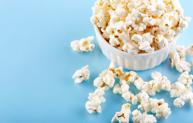 Popcorn on a bright blue background. Film. Fast food. Corn