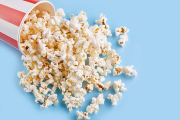 Pop the corn in a red white cup on a bright blue background. Film. Fast food. Corn