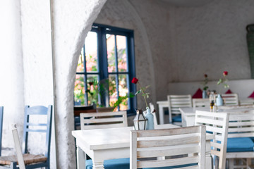 Interior of outdoor greek restaurant with white and blue chairs.