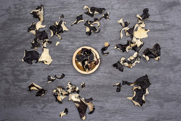 Lot of slices of dry black mushroom jew ear variety with wooden bowl flatlay on grey stone