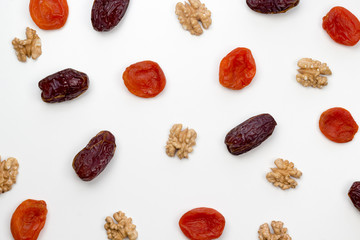 Dates, dried apricots and walnuts on the white background. Top view, flat lay, copy space, pattern