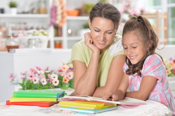 Portrait of little girl with her mother doing homework