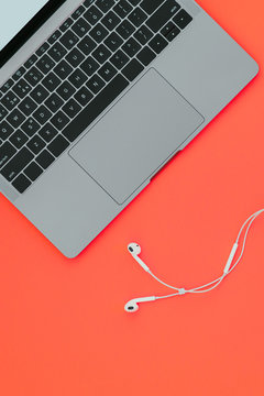 Modern Nice Notebook And White Headphones On A Red Background, Top View. Flatlay.Copyspace. Work On A Laptop With Music.