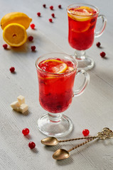 Cranberry tea or hot healthy winter sangria in glasses with fresh lemons on the gray concrete kitchen background