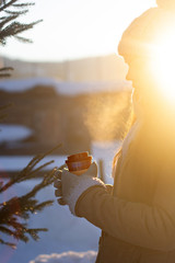 Beautiful Woman Going To With Coffee Walking in Winter. Portrait Of  Woman Holding Cup Of Hot Drink In Hand. Coffee to go. Sun rays.