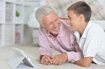 Grandfather with grandson using laptop while lying on floor 