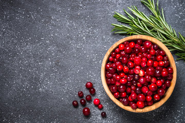 Cranberry and rosemary on black stone background. 