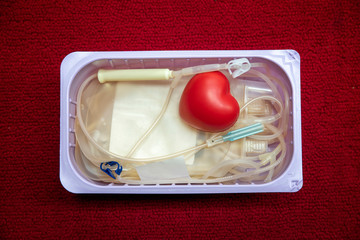 A red heart bouncy ball with blood bag in basket. Healthcare and charity. Blood donation concept