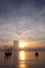 Fototapeta premium Sunrise, the colors of the morning sky, with the fishermen preparing the boat to go out to fish.