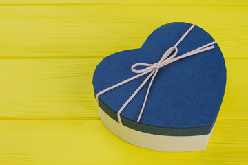 Blue heart box. Close up, top view. Yellow wood background.