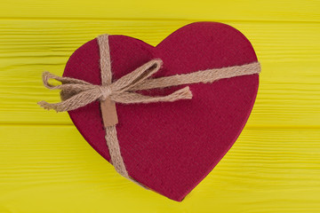 Valentine heart red gift box. Close up. Yellow wooden Background.