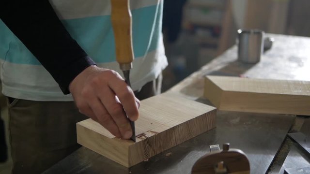 A man works a chisel and a mallet