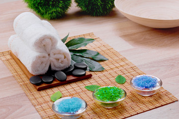 Beautiful spa and wellness setting composition on massage table in relax center on blackboard with copy space.Towel, Salt, Plumeria Flower, Hot stones Bowl for spa therapy.Spa  products