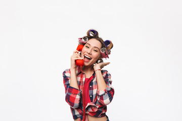 Cheerful housewife with curlers in hair standing