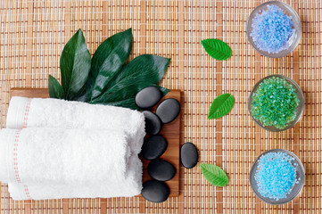 Top view of hot stones setting for massage treatment on blackboard with copy space.Towel, Salt, Plumeria Flower, Bowl for spa therapy with Copy space. Beautiful spa composition on massage table
