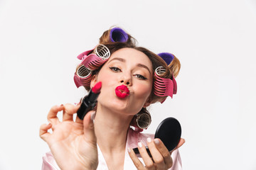 Cheerful housewife with curlers in hair wearing robe
