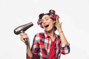 Cheerful housewife with curlers in hair standing