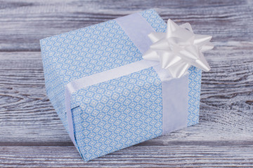 Beautiful gift box on wooden background. Gift box wrapped in blue paper with white bow on vintage...