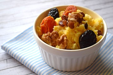 Useful porridge of corn grits and dried fruits on a wooden background.