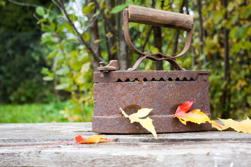 vintage iron next to autumn leaves on an old wooden table in the garden