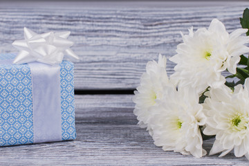 Gift box and white chrysanthemum flowers. Beautiful gift box and fresh flowers on wooden background. Holiday greeting card.