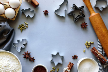 Cooking Christmas cookies. Ingredients for gingerbread dough: flour, eggs, sugar, cocoa, cinnamon sticks, anise stars and cookie cutters on gray wooden background. Flat lay. Top view. Copy space