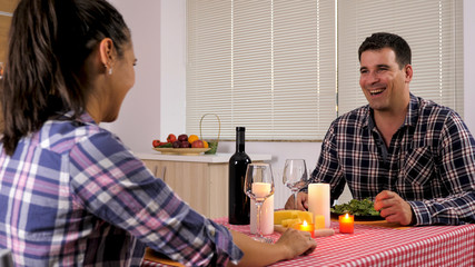 Young man and woman talking while having a romaning dinner. Sweet moment.