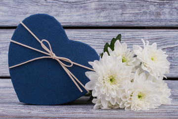 Valentines Day gift box and flowers. Blue heart shaped present box and white chrysanthemums on wooden background. St. Valentines Day greeting card.