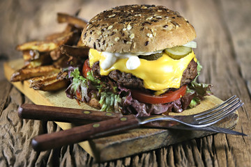 homemade cheeseburger and French fries on rustic wooden background