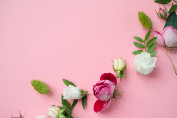 Frame of purple and pink roses, white Lisianthus and different flowers on pink background.