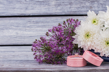 Ring in gift box flowers close up. Engagement ring in a gift box with bright bouquet of flowers on rustic wooden background.